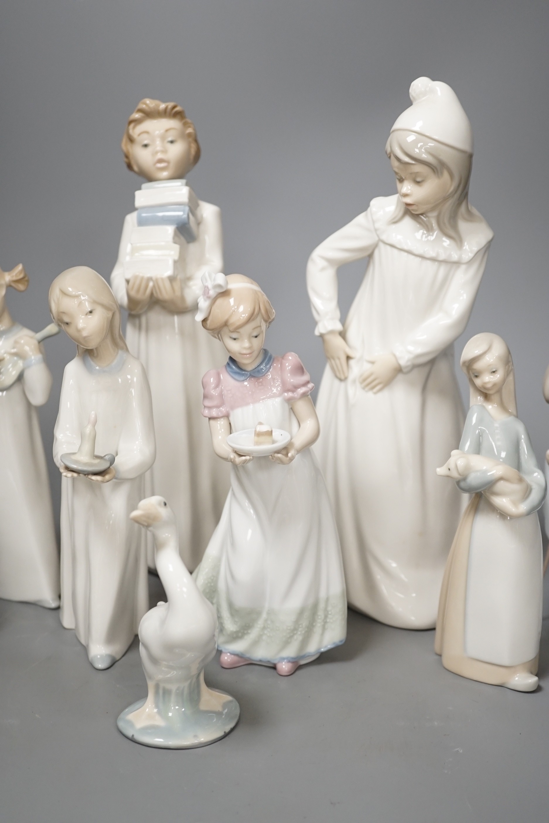 Seven Lladro figures together with two Nao figures. Tallest 29cm